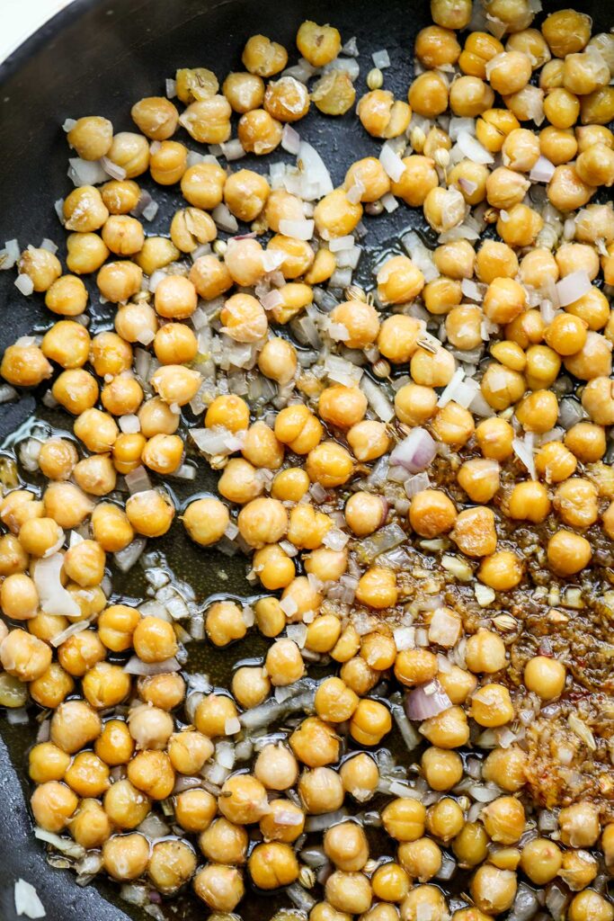 Adding the lemon sticky sauce over the chickpeas in the pan.