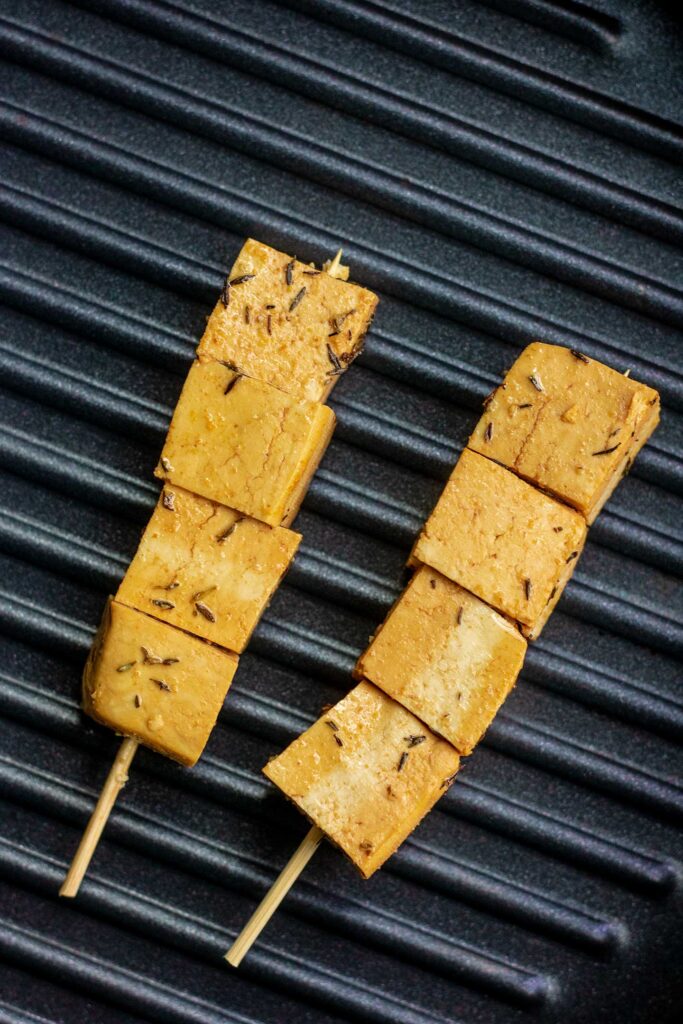 Marinated skewered tofu on a grill pan.