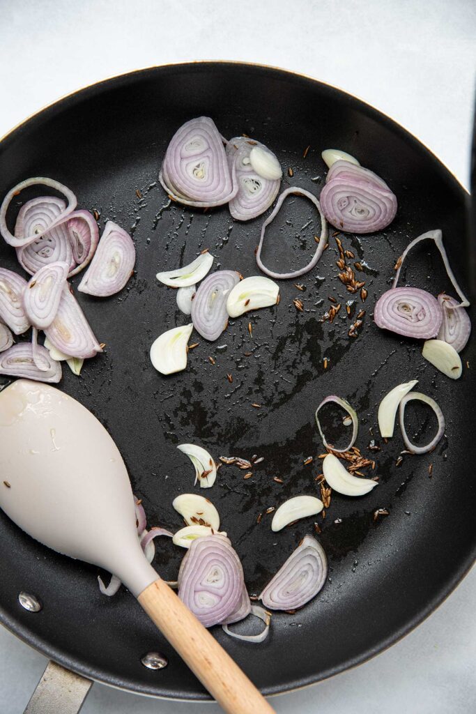 Sauteing shallots, garlic and cumin together.