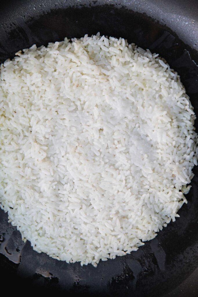 Forming the rice in a flat circle in a sauté pan.