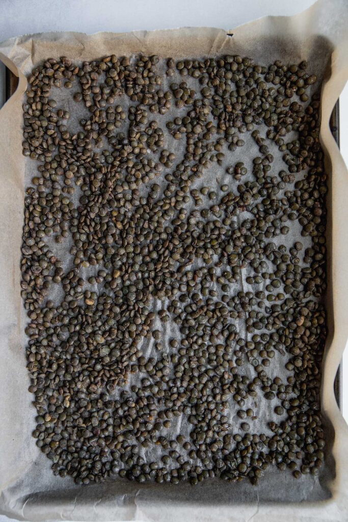 Seasoned lentils on a parchment lined sheet pan.