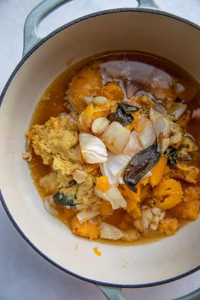 Butternut squash, garlic, nutritional yeast, onion and vegetable broth in a soup pot.