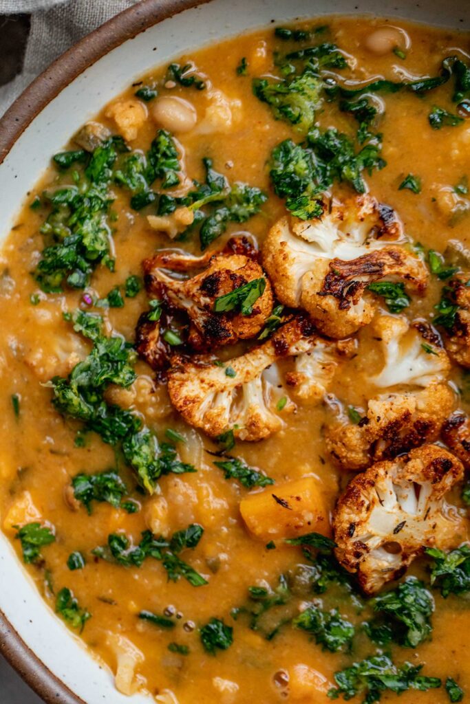 Creamy sweet potato soup in a bowl topped with roasted cauliflower and gremolata.