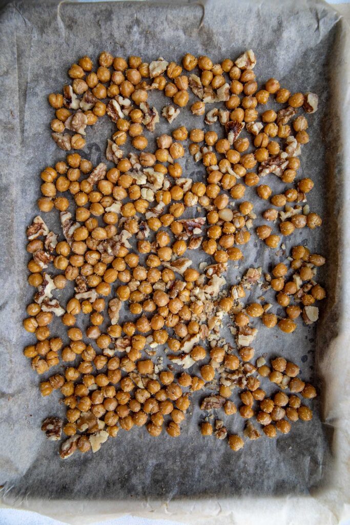 Combining the chickpeas and walnuts together on a baking tray with seasoning.