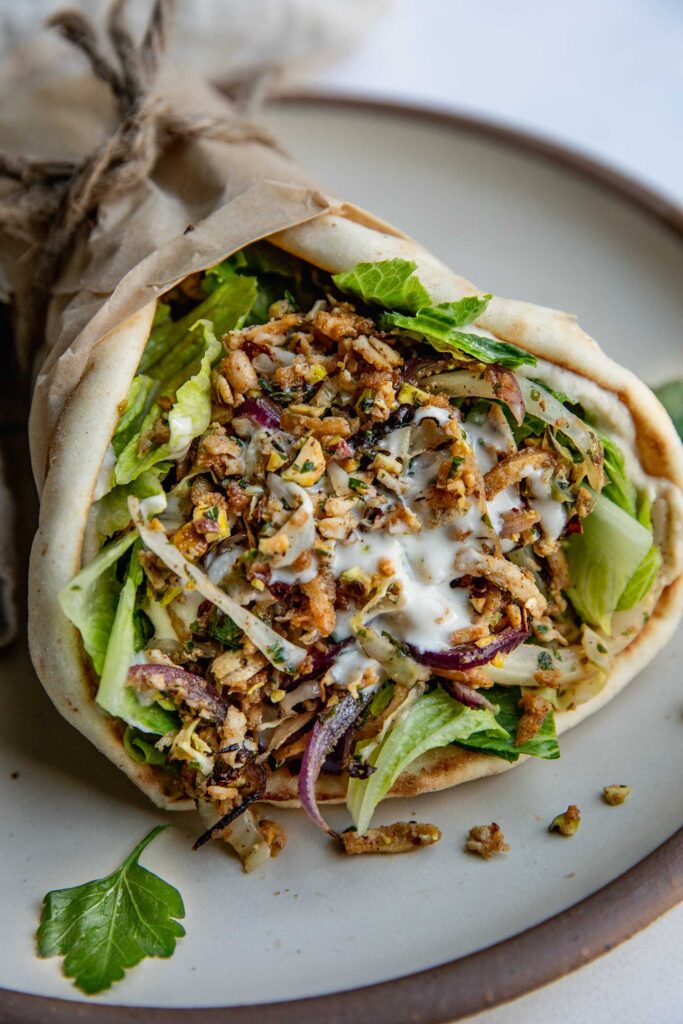 A pita wrap loaded with za'atar pistachio coated shredded tofu, hummus and lettuce.