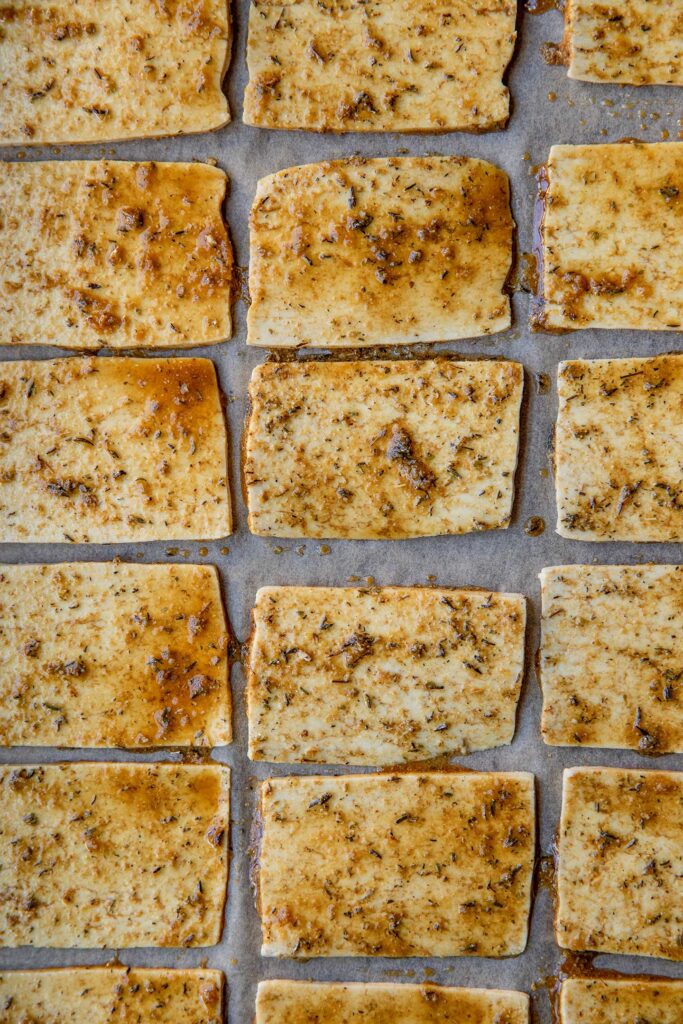 Marinated tofu slices on a baking tray.