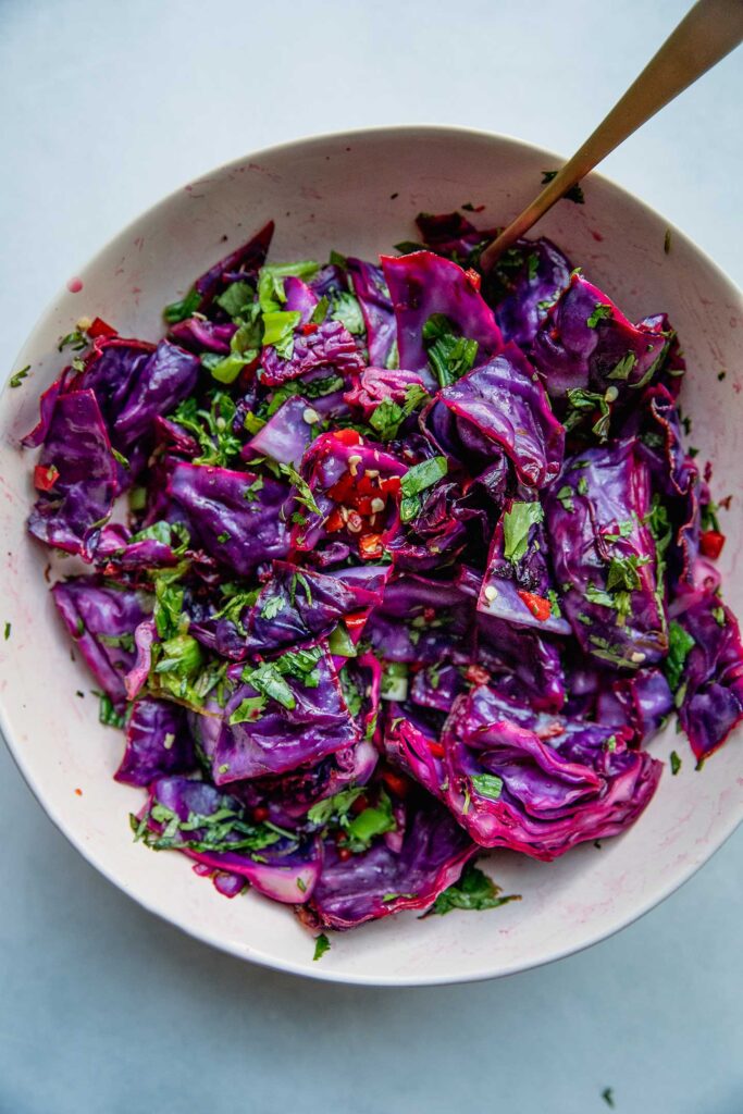 Cabbage salad mixed together in a pink bowl.