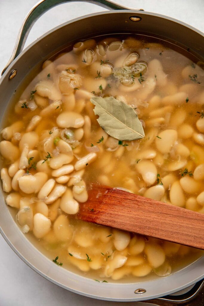 Stirring the beans into the broth in a skillet.
