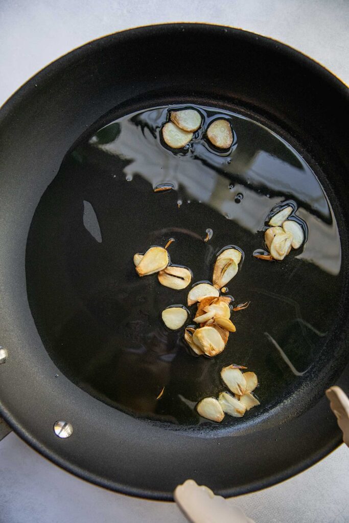 Toasting garlic slices in a pan.