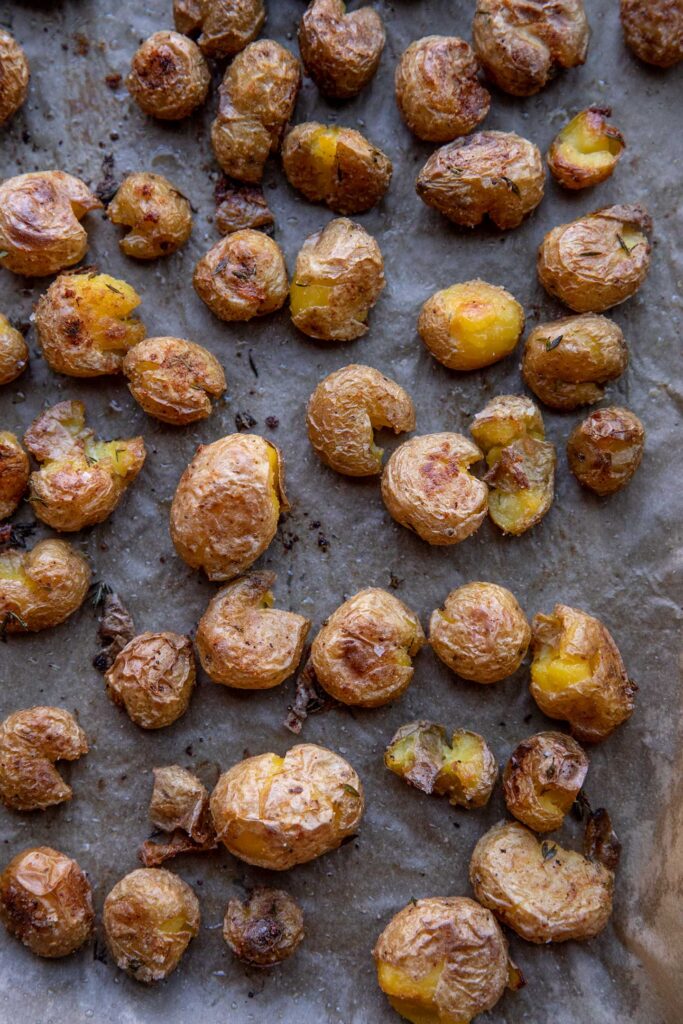 Roasted smashed potatoes on a baking tray.