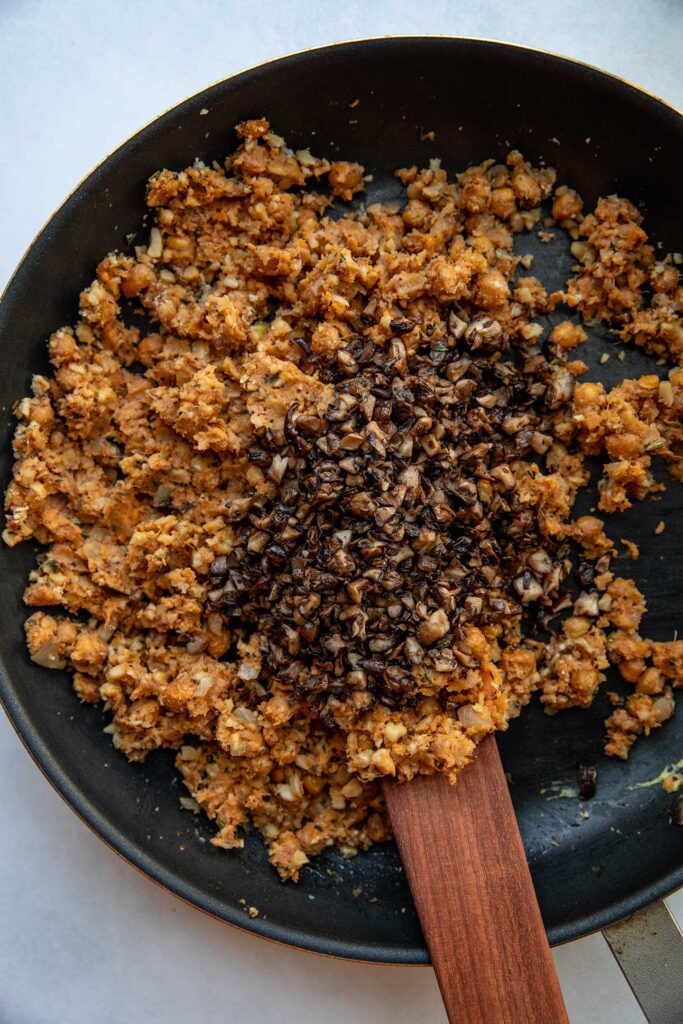 Folding in the sauteed mushrooms into the filling in a pan.