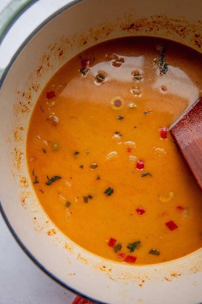 Stirring the broth and coconut milk together in a pot.