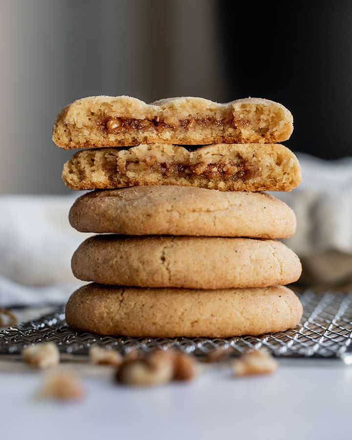 Stack of cookies with the top cookie broken in half to show the cinnamon walnut filling.