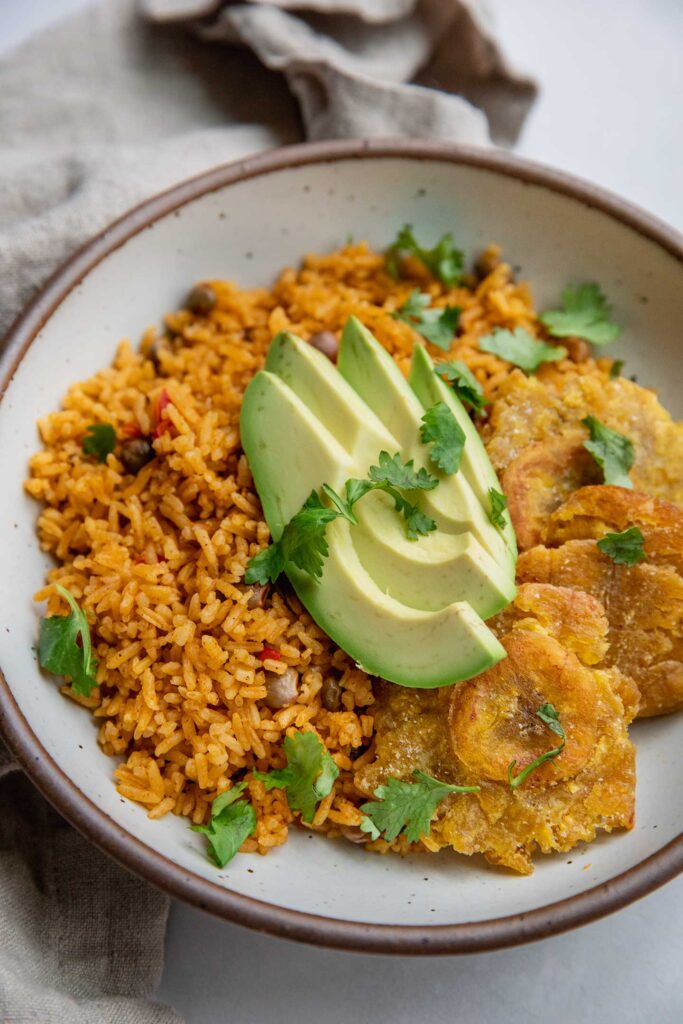 Bowl of moro served with baked plantains and avocado slices.