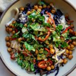 A bowl of roasted cabbage salad over white rice, topped with roasted chickpeas, herby salad and miso dressing.