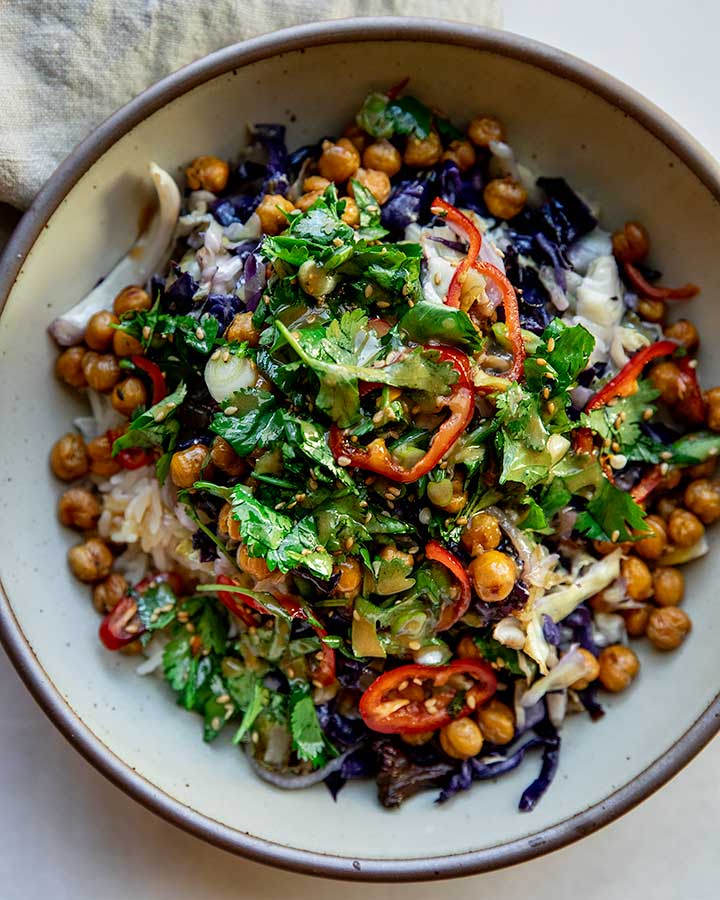 A bowl of roasted cabbage salad over white rice, topped with roasted chickpeas, herby salad and miso dressing.