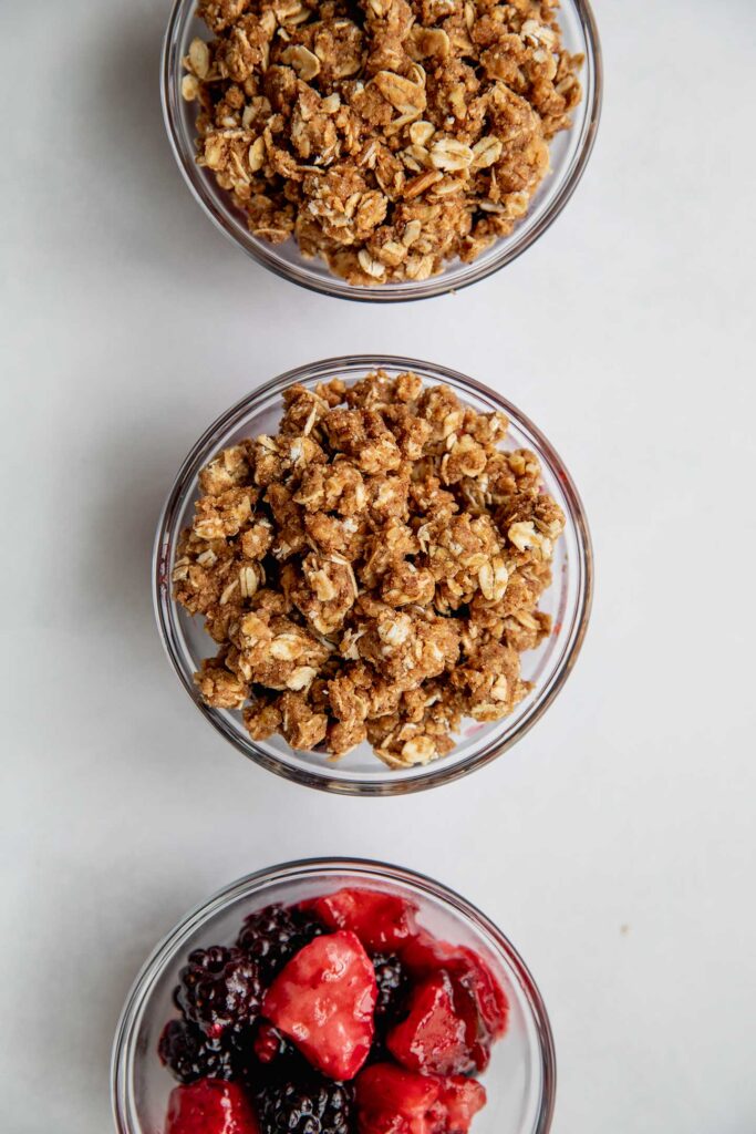 Two baking dishes filled with berries topped with crumble and one baking dish filled with berries only.