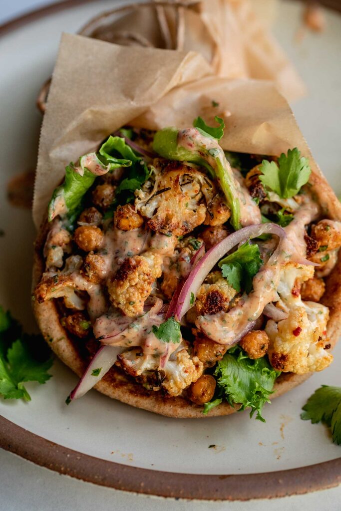 A pita wrap stuffed with charred cauliflower, chickpeas, chipotle sauce, pickled onions and lettuce.