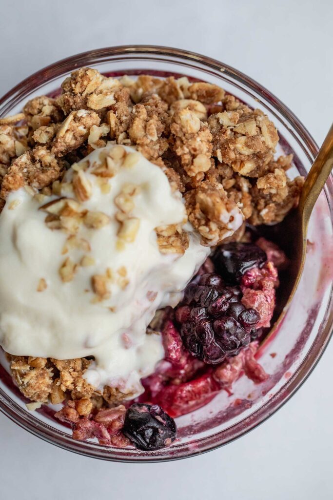 Taking a spoon of the crumble, berries and yogurt from the baking dish.