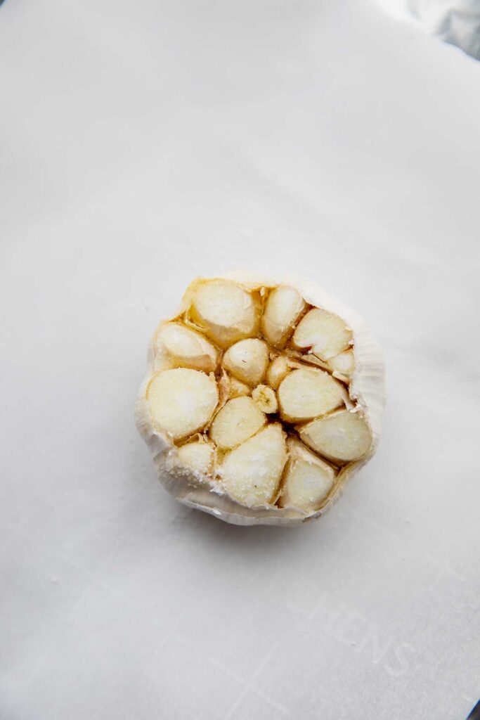 Garlic bulb with exposed cloves on a packet of foil.