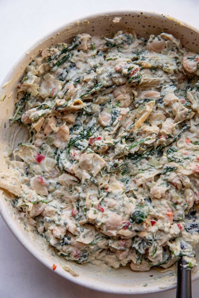 Artichoke spinach white bean dip mixed together in a bowl.