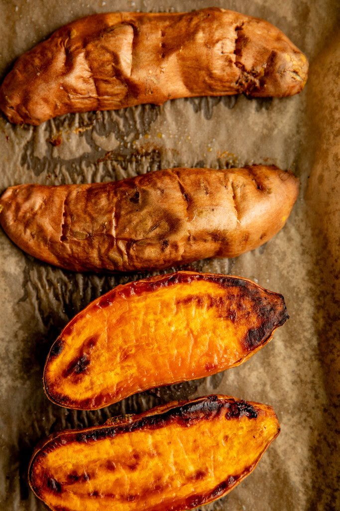 Baked sweet potato halves on a baking tray.