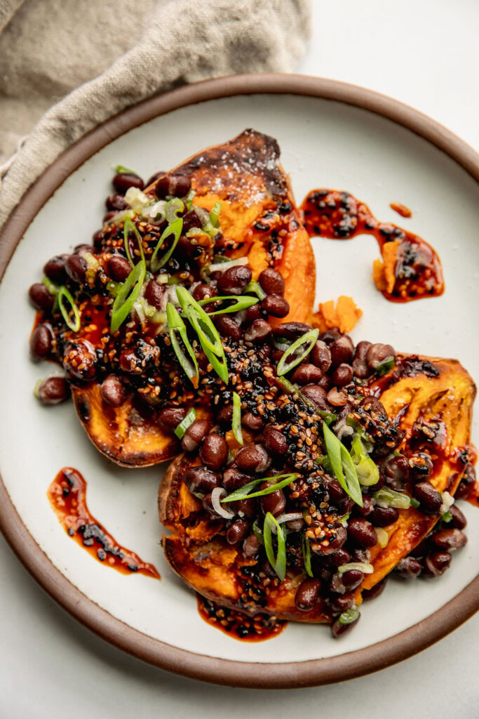 Scallion black bean stuffed sweet potatoes topped with a gochujang sauce and scallions.