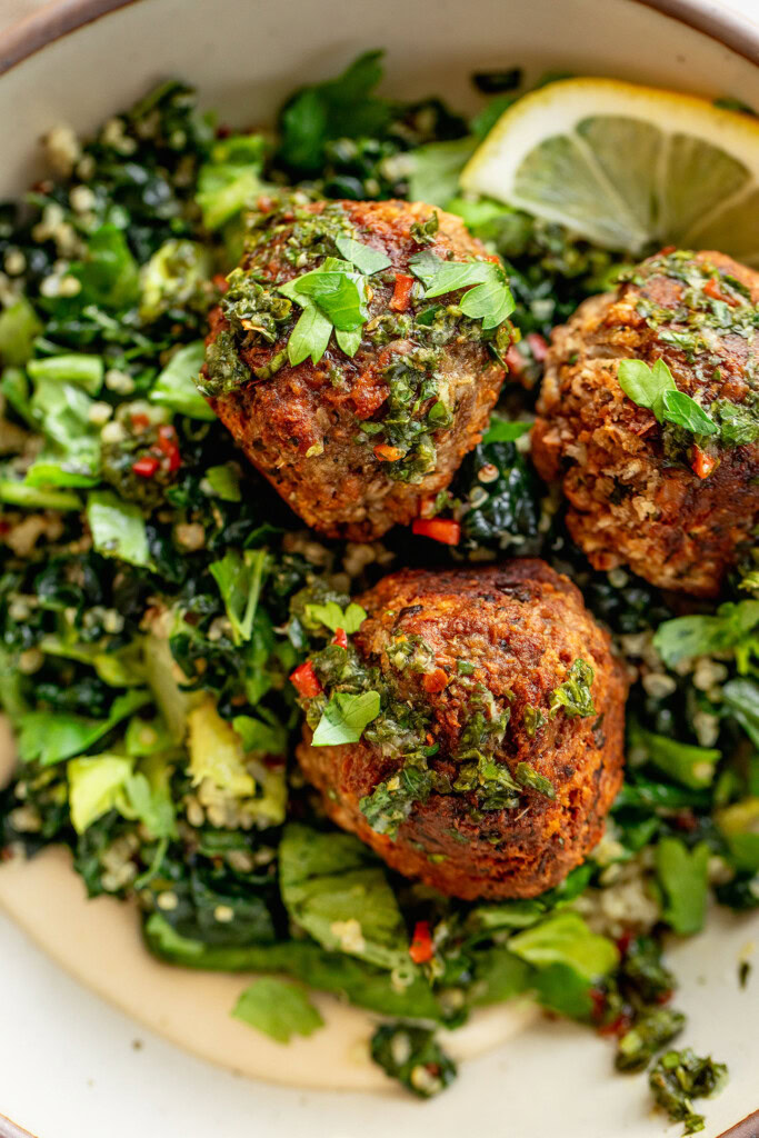 Close up of the chimichurri meatballs on top of a bed of chimichurri quinoa and greens.