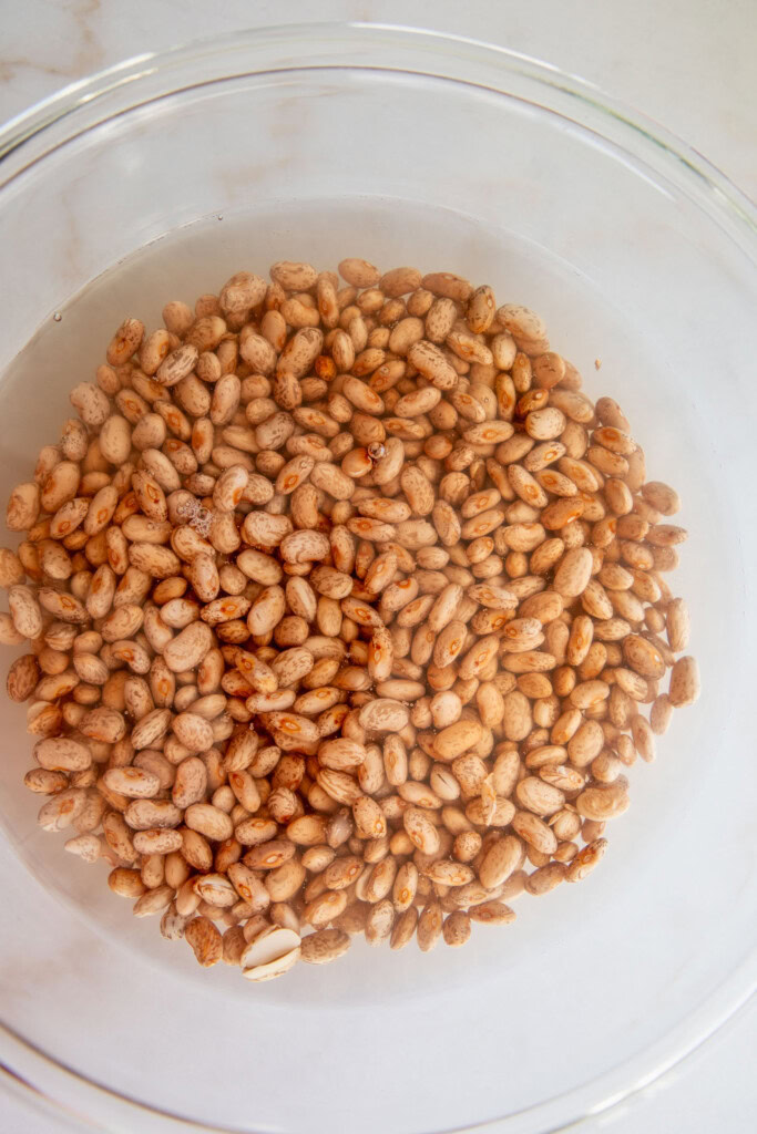 Soaked pinto beans in a large bowl.