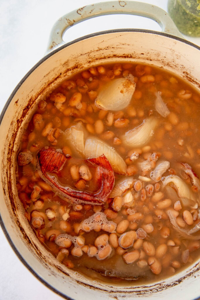 The cooked beans with onions, garlic and bay leaf in a pot.