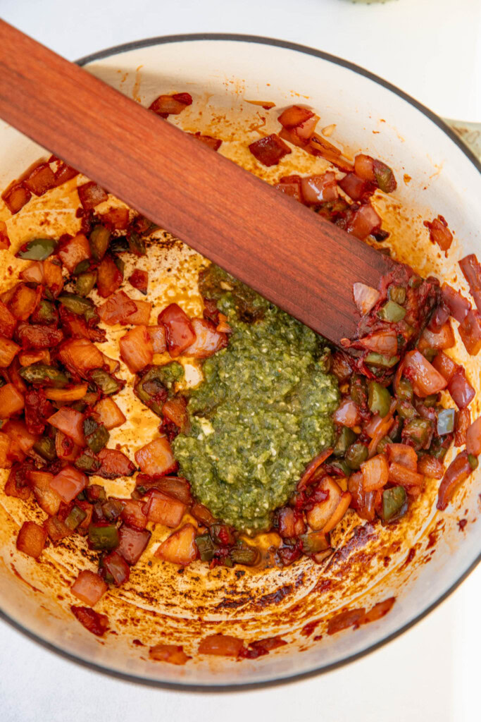 Adding the sofrito to a pot of caramelized aromatics.