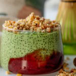 Close up of a jar of matcha pudding served with a dollop of strawberry jam and pie crust crumble on top.