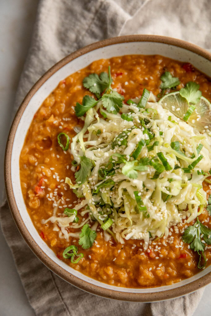 Bowl of caramelized sweet potato scallion lentils topped with cabbage slaw.