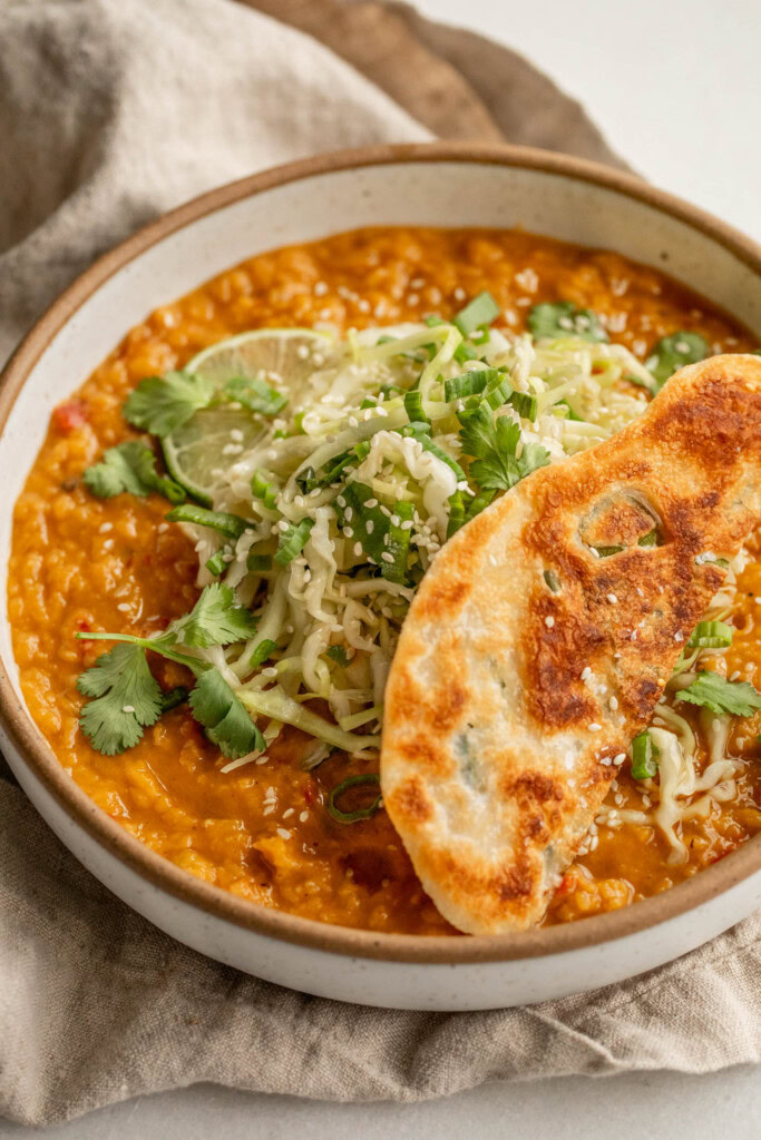 Creamy red lentils topped with cabbage slaw and a scallion pancake.