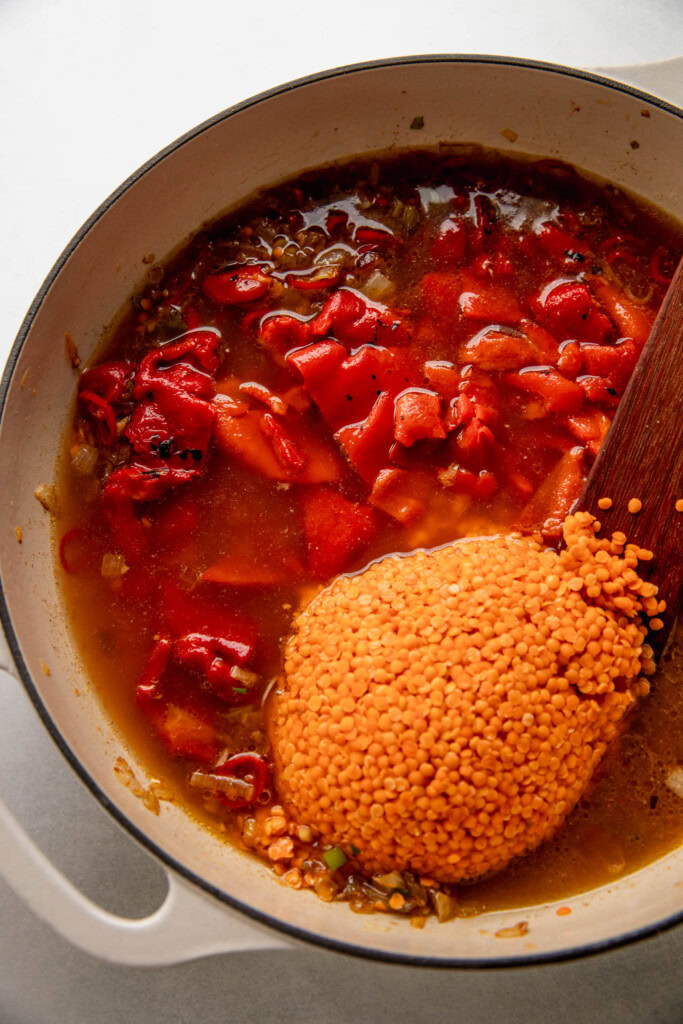 Adding the roasted bell peppers and lentils in a pan with aromatics and broth.