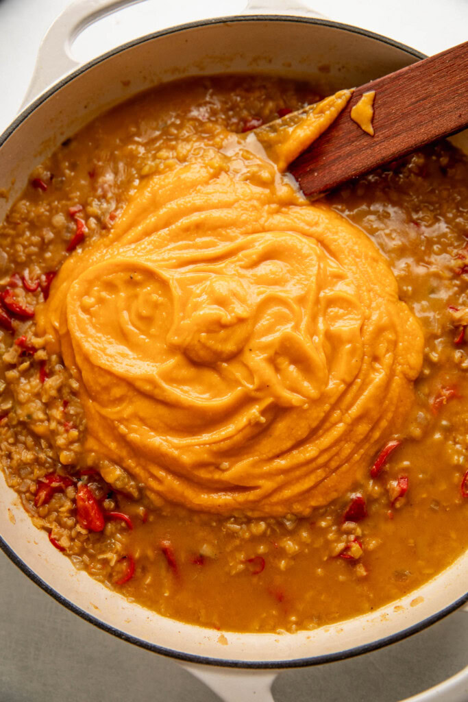 Adding the blended sweet potato into the pan of cooked lentils.