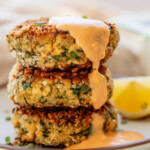 A stack of three tofu patties on a plate with kimchi mayo drizzled on top.