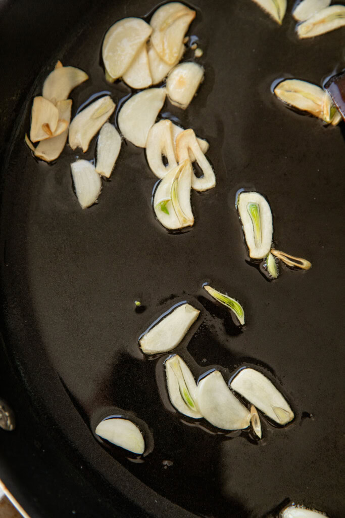 Cooking garlic slices in a pan with oil until golden.