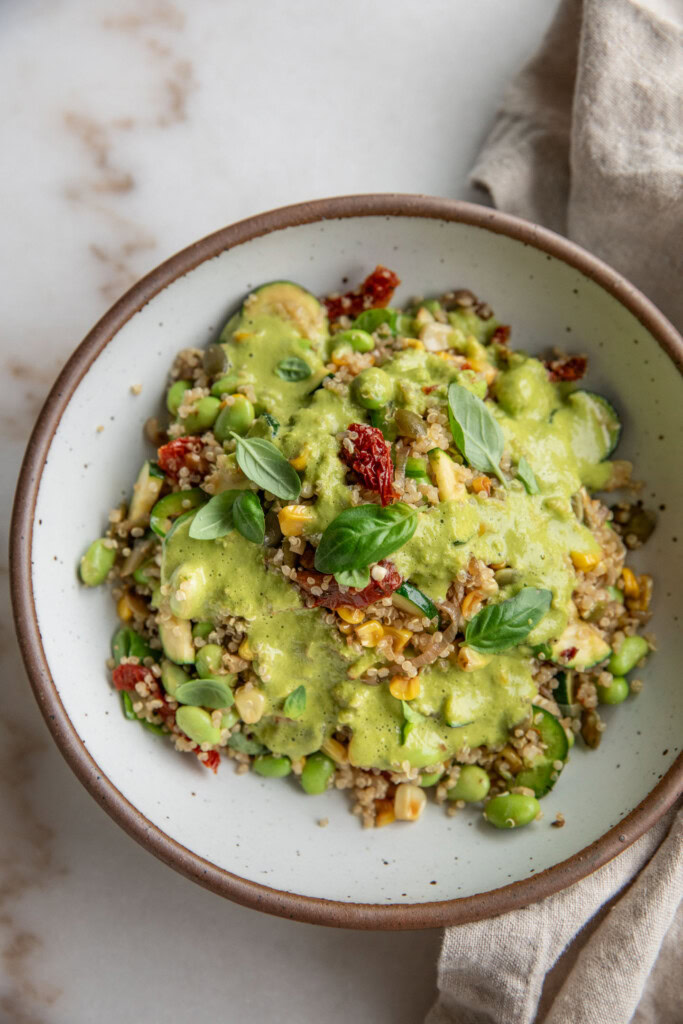Bowl of corn and quinoa salad topped with a drizzle of creamy jalapeño lime dressing.