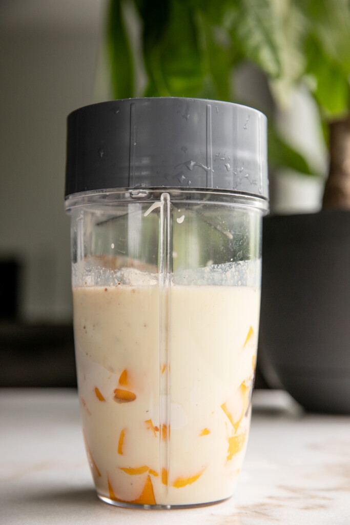 Blending the mango milk together in a blender cup.