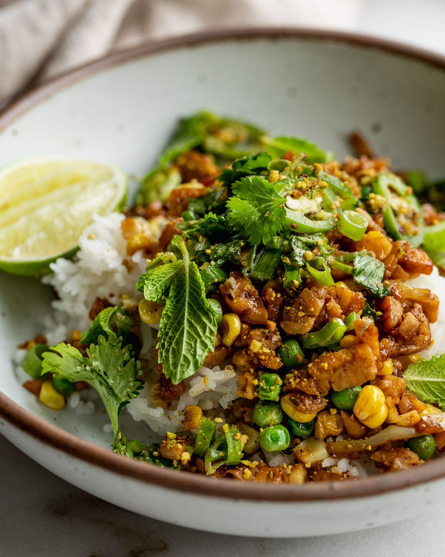 Mound of rice topped with sticky tempeh and scallion salad.