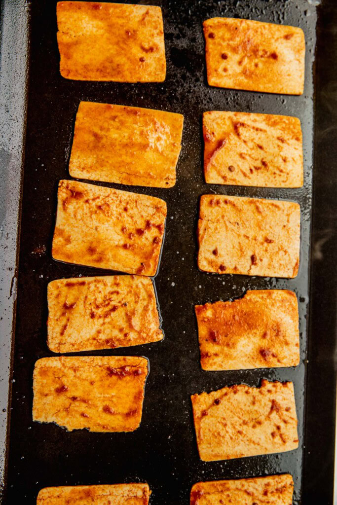 Cooking the marinated tofu slices on a griddle.
