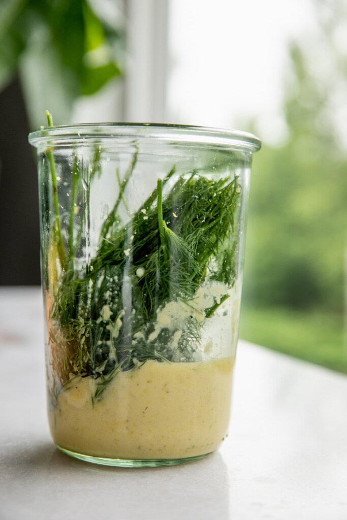 The scallion garlic dressing being blended together with fresh dill.