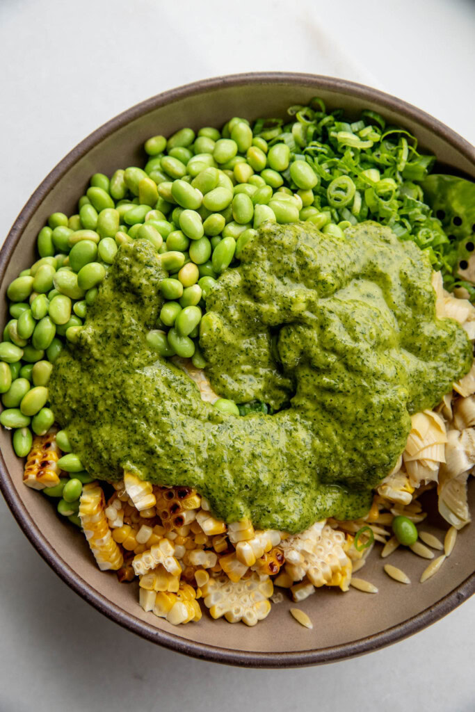 The creamy scallion dill dressing over top of the orzo salad ingredients in a bowl.