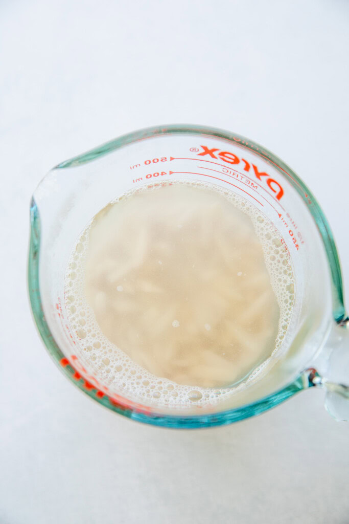 Soaked almonds in a measuring cup with hot water.