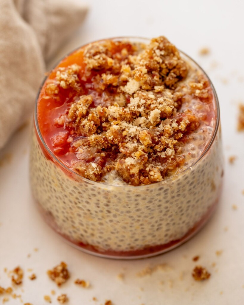 Close up of a peach cobbler chia pudding cup layered with cooked peaches, chia pudding, and the cobbler crumb on top.