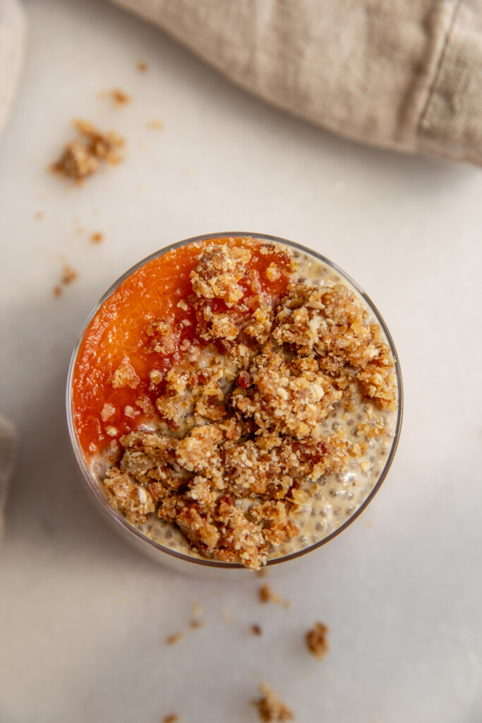 A serving of chia pudding topped with cooked peaches and the cobbler crumb.