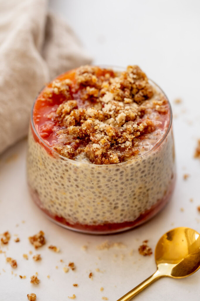 Cup of peach cobbler chia pudding showing layers of cooked peaches, chia pudding, and cobbler crumb.