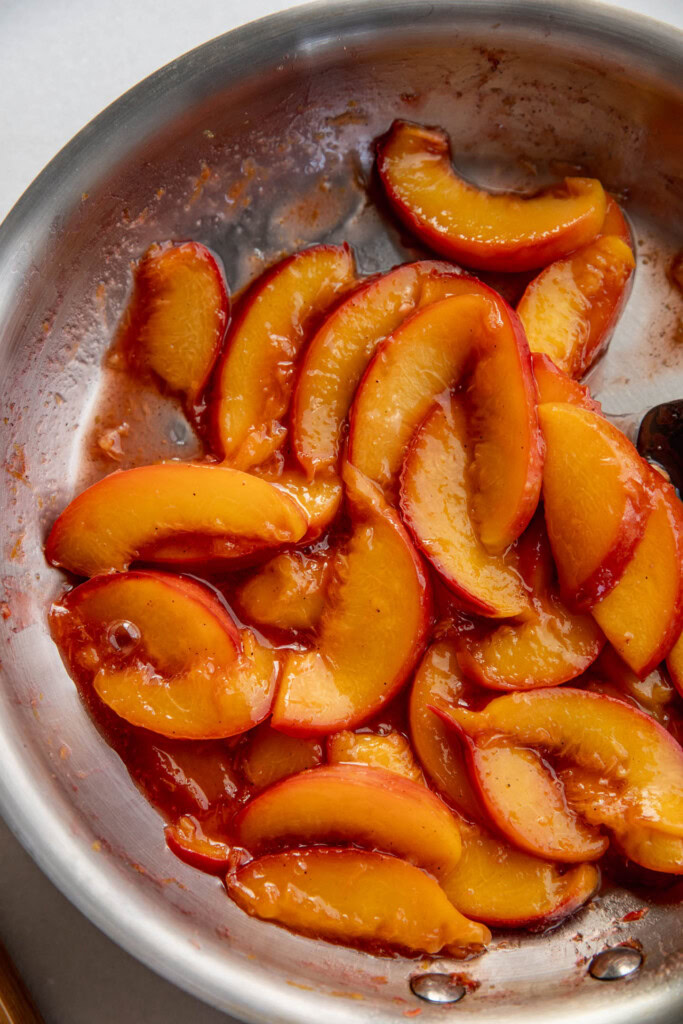 Peach slices cooked down in a pan.