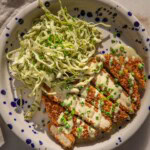 Plate loaded with cut tofu cutlet served with lemon dill slaw and a drizzle of the dressing on top of the tofu.